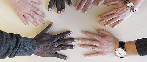 Hände in verschiedenen Hautfarben auf einem Tisch