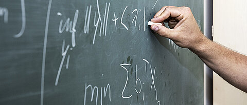 Hand is writing on a blackboard