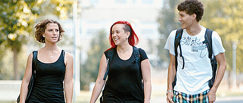 Drei Studierende gehen über den Campus